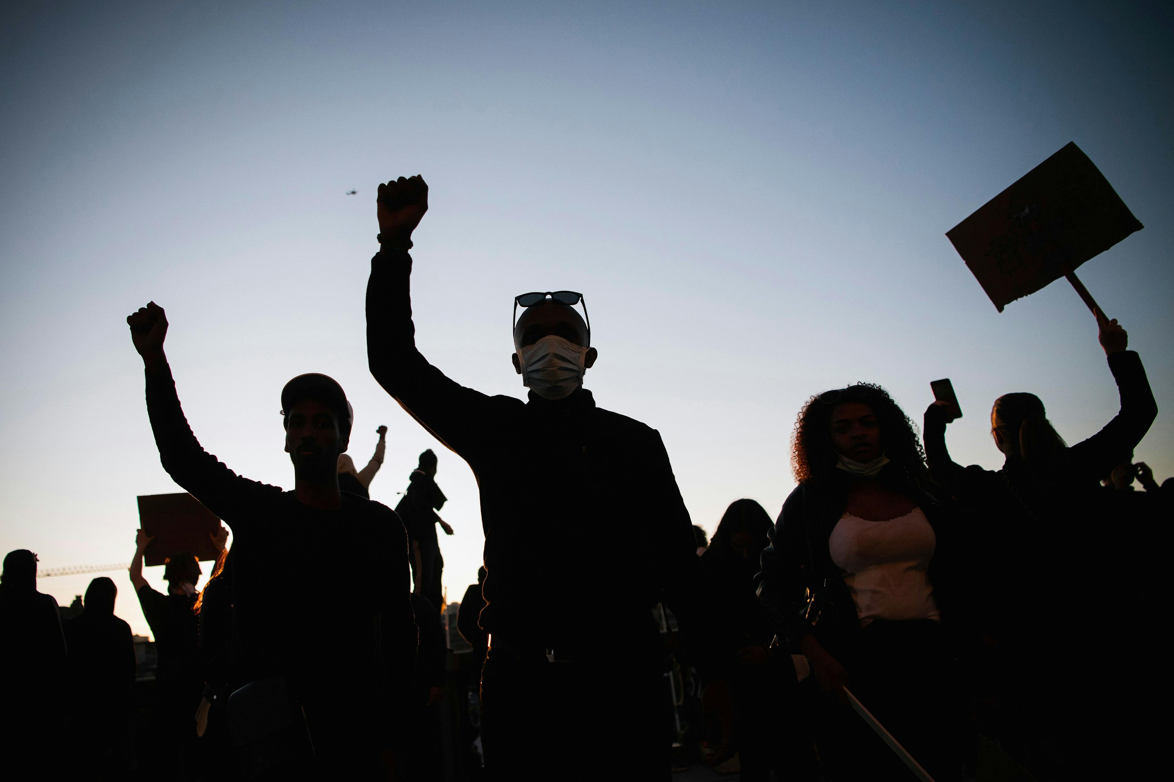 image of black figures protesters with signs and fists raised 