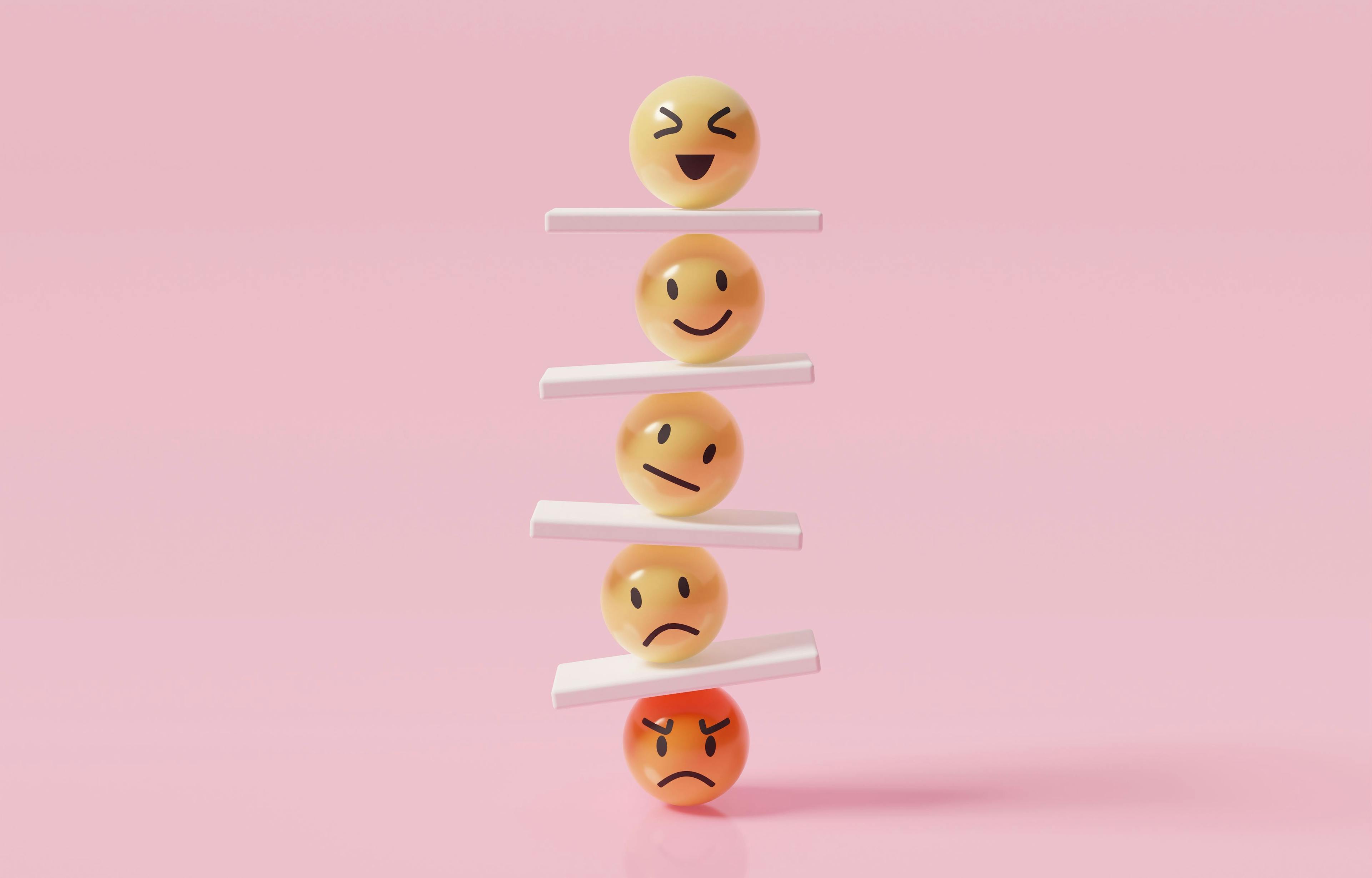 A stack of five 3-D emoticons showing various emotions, balanced on each other with white slabs in between.