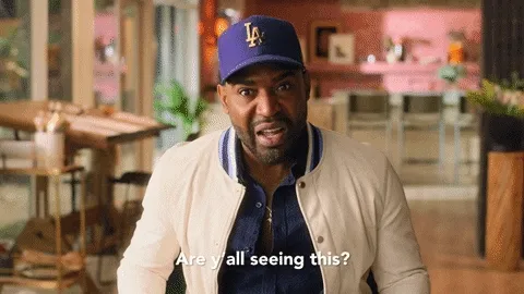 Karamo Brown in purple baseball cap pointing with Are y'all seeing this as a caption